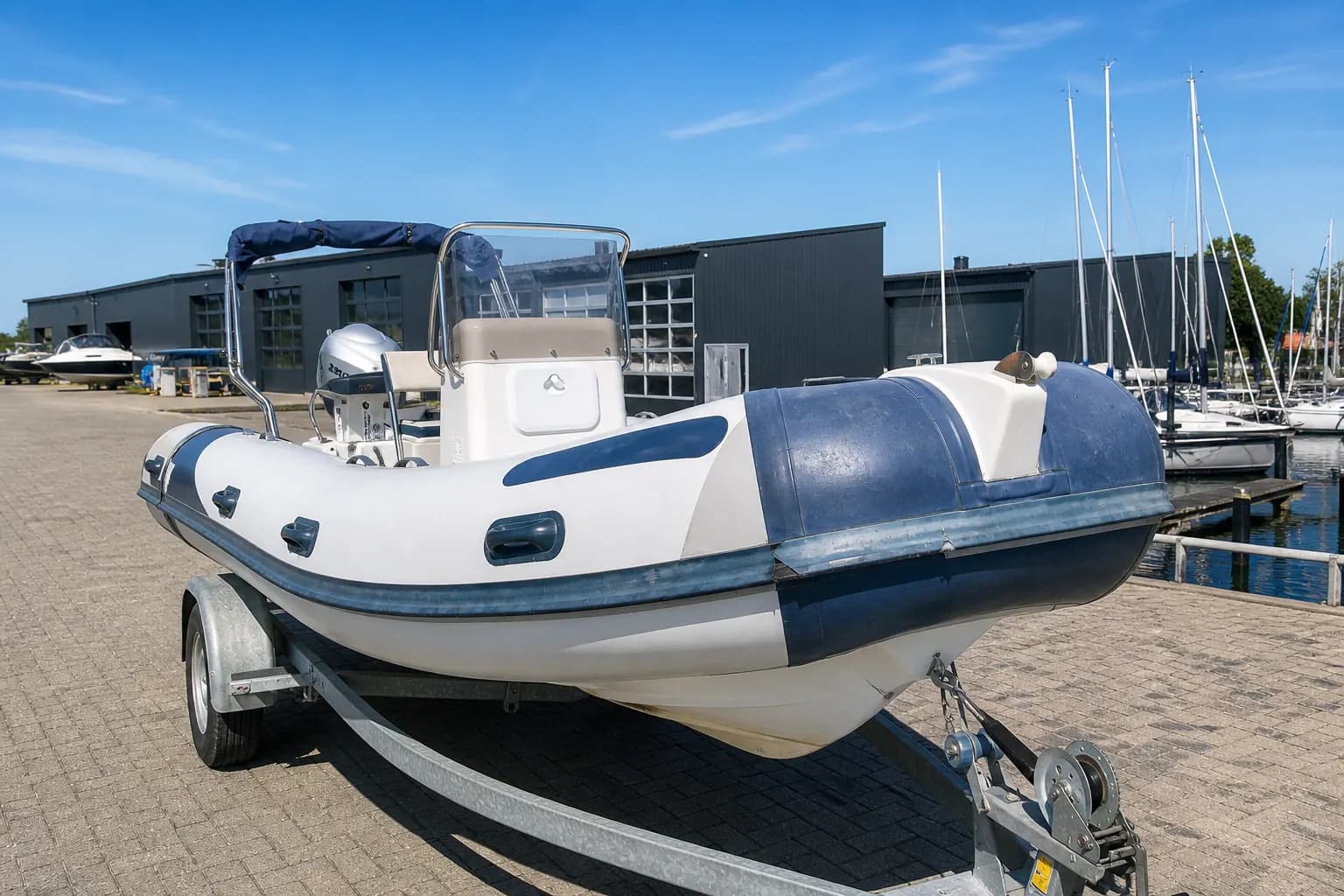 Een RIB op een trailer, met verbleekte en vervuilde grijze tubes en een beschadigde wrijfrand